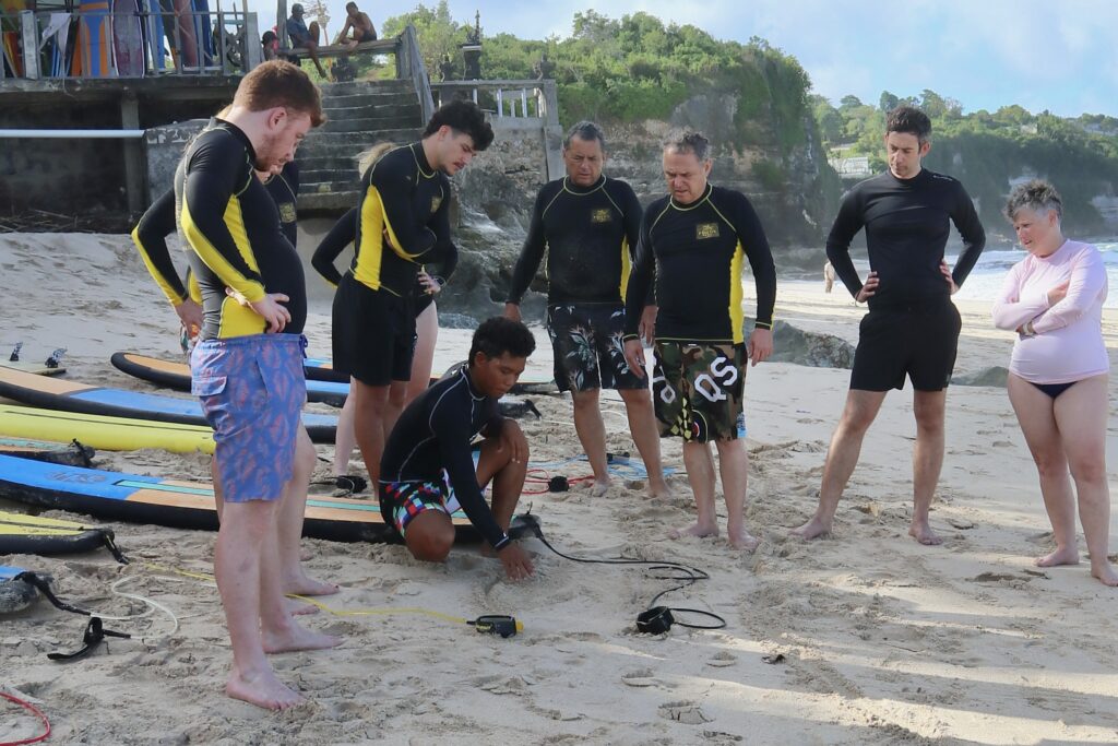 Surf instructor explaining beach layout and wave channels to students before lesson in Dreamland Beach, Uluwatu Bali