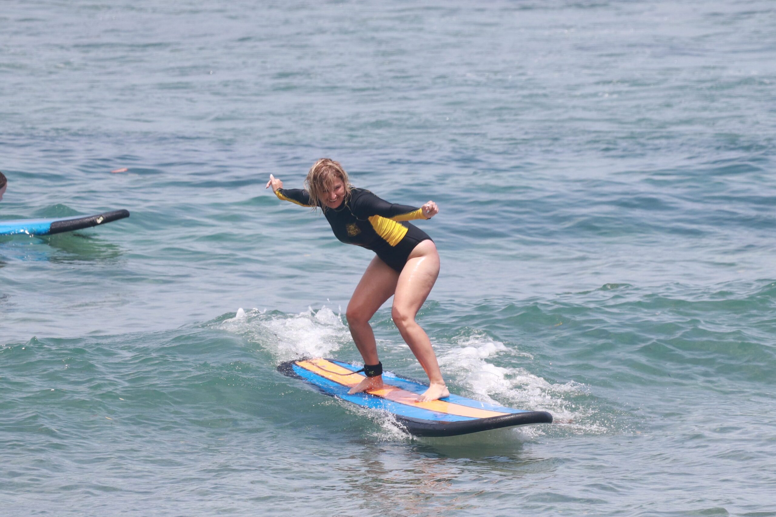 A happy beginner surfer enjoying surf lesson at Padang-Padang Beach in Uluwatu Bali